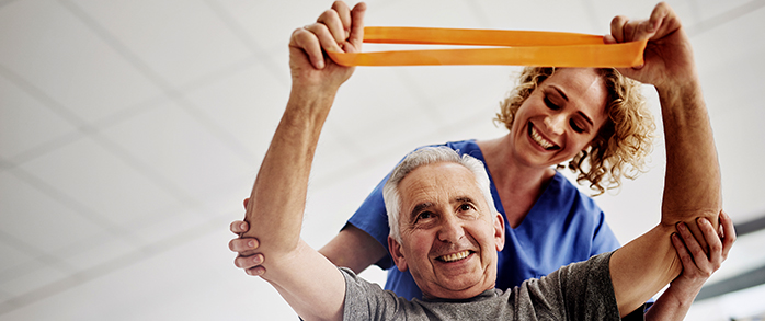 Medical Tech assisting older patient with exercise Band